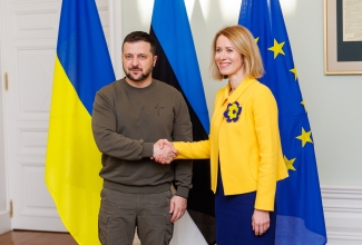 Ukraina president Vladimir Zelenskõi vasakul, peaminister Kaja Kallas paremal lippude taustal kätt surumas