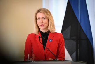 Peaminister Kaja Kallas pressiavaldust tegemas, taustal Eesti lipp. 